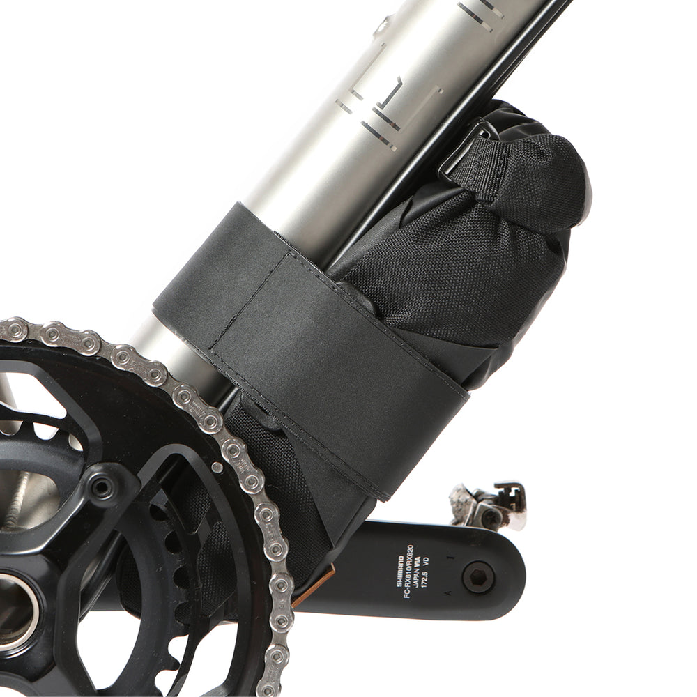 A black Restrap downtube bag attached to a bicycle frame beneath the downtube, featuring a roll-top closure and velcro strap.