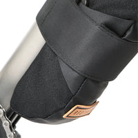 closeup of A black Restrap downtube bag attached to a bicycle frame beneath the downtube, featuring a roll-top closure and velcro strap.