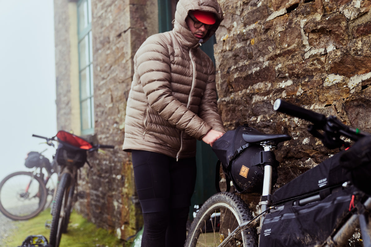 rider packing up a restrap saddle bag at a countryside bothy