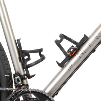 A black side release bottle cage mounted on a bicycle frame, with a side entry opening.