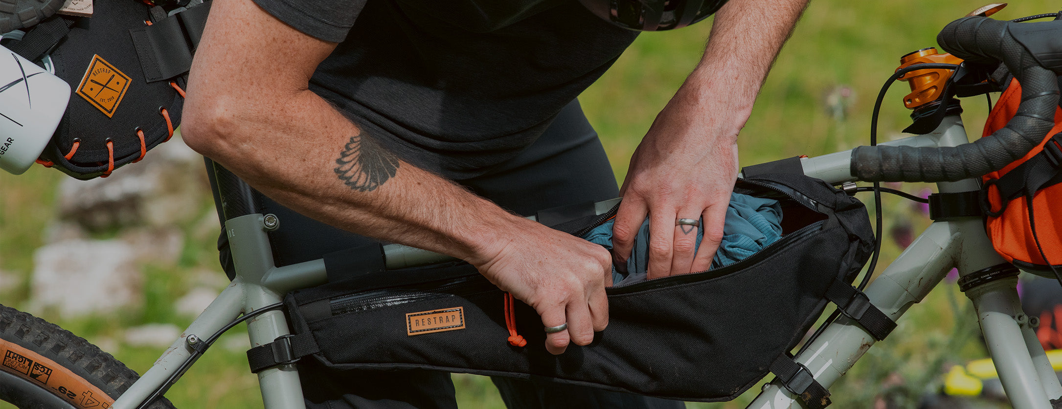 closeup of man packing restrap full frame bag with rain jacket