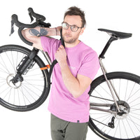 A black hike a bike harness attached to the frame of a bicycle, designed for carrying the bike on one's back.