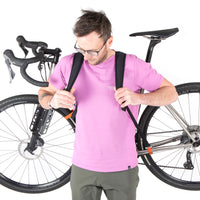 A black hike a bike harness attached to the frame of a bicycle, designed for carrying the bike on one's back.