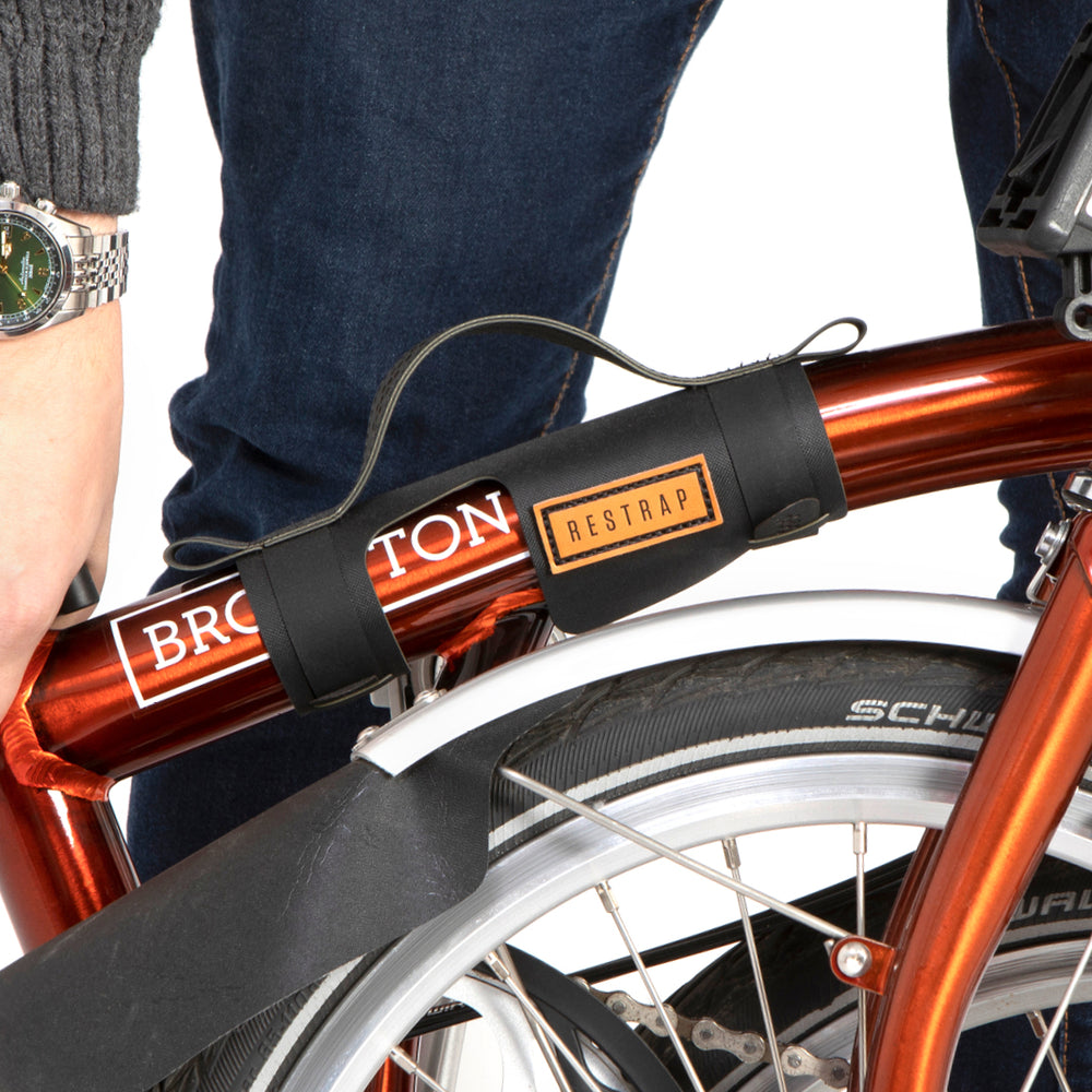 A black carry handle attached to the top tube of a red folding bike with the brand name Restrap visible.