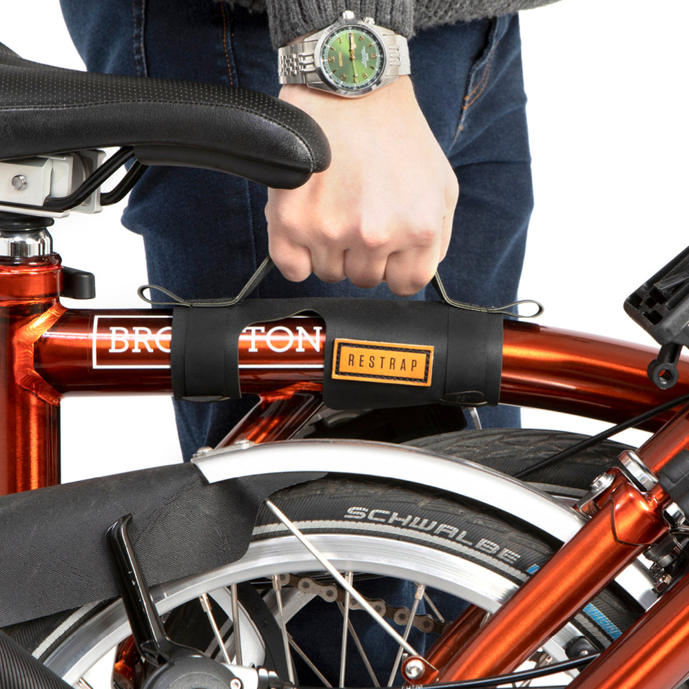 A black carry handle attached to the top tube of a red folding bike with the brand name Restrap visible.