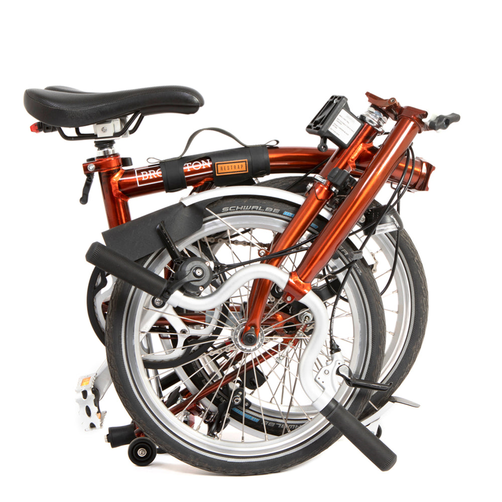 A black carry handle attached to the top tube of a red folding bike and the bike shown in it's folded state