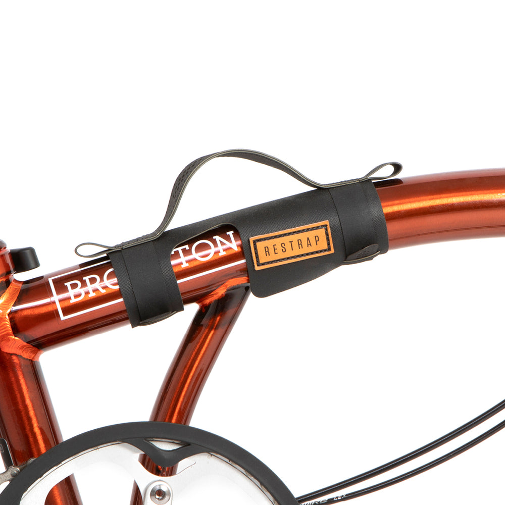 A black carry handle attached to the top tube of a red folding bike with the brand name Restrap visible.