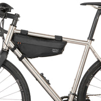 A small black race frame bag attached to the frame of a bicycle, designed for bikepacking.