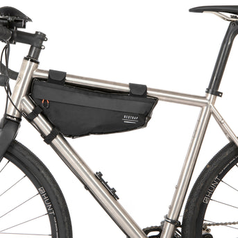 A small black race frame bag attached to the frame of a bicycle, designed for bikepacking.