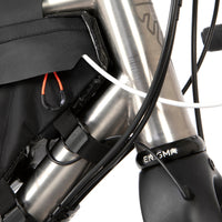 closeup of the straps of a small black race frame bag attached to the frame of a bicycle, designed for bikepacking.