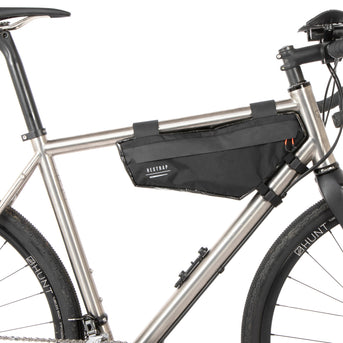 A small black race frame bag attached to the frame of a bicycle, designed for bikepacking.