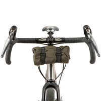 A black metal bumper bar mounted on a bicycle handlebarwith a jacket attached for storage