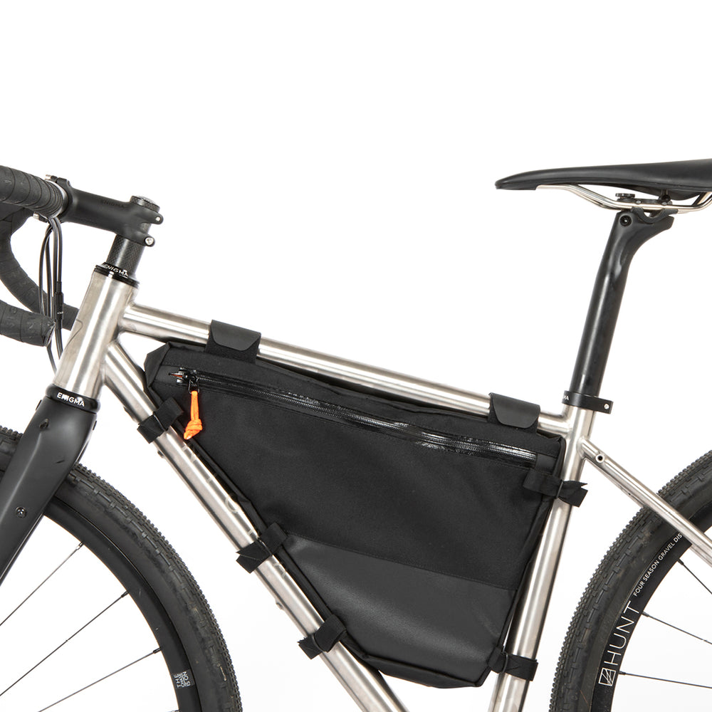 A small black full frame bag attached to the down tube of a bicycle, featuring adjustable straps, shown from the non drive side