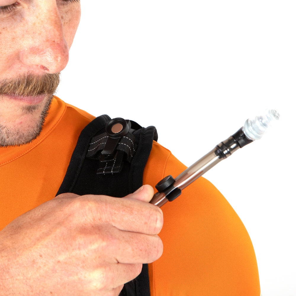 Person clipping a hydration hose onto a vest strap