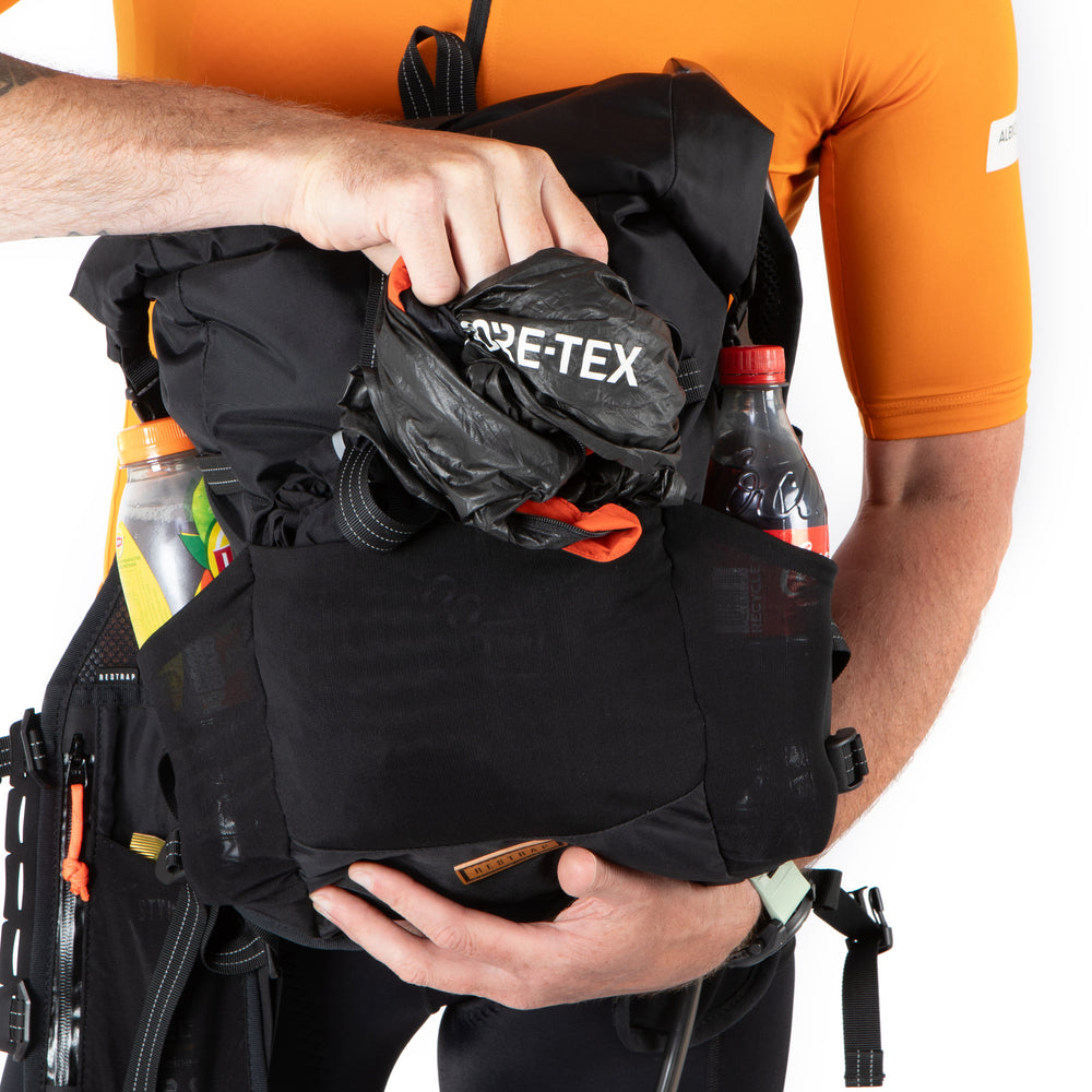 Person holding a black backpack with a visible brand logo on a white background