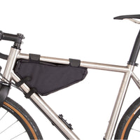 A black Restrap frame bag small attached to the down tube of a bicycle, shown from the non drive side