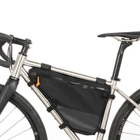 A small black full frame bag attached to the down tube of a bicycle, featuring adjustable straps, shown from the non drive side